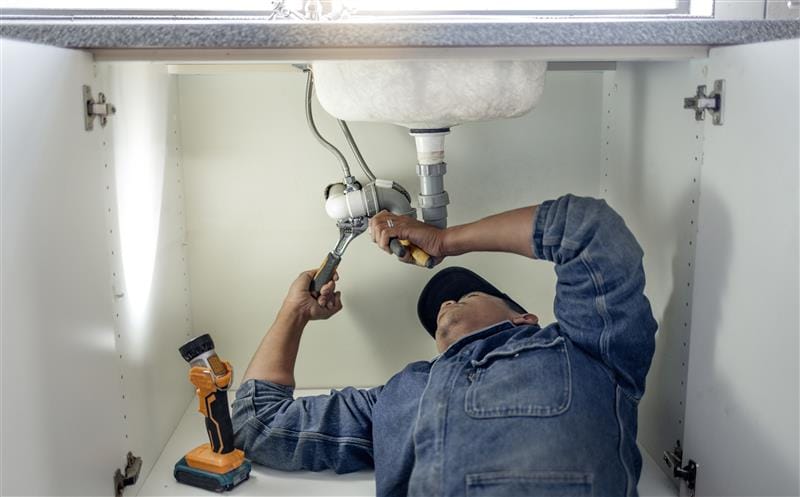 Plumber repairing kitchen sink drain pipes in Venice, Florida