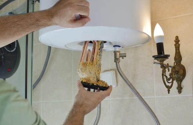 Technician removing mineral buildup from a water heater in Venice